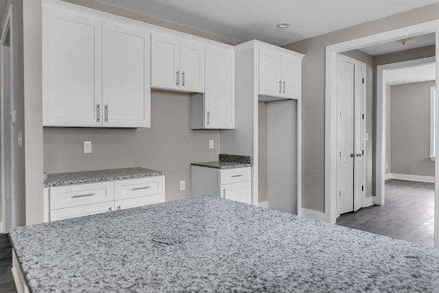 kitchen featuring hardwood / wood-style flooring, white cabinetry, and light stone countertops