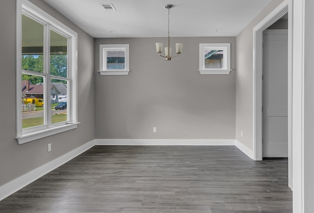 unfurnished dining area with dark hardwood / wood-style floors and an inviting chandelier