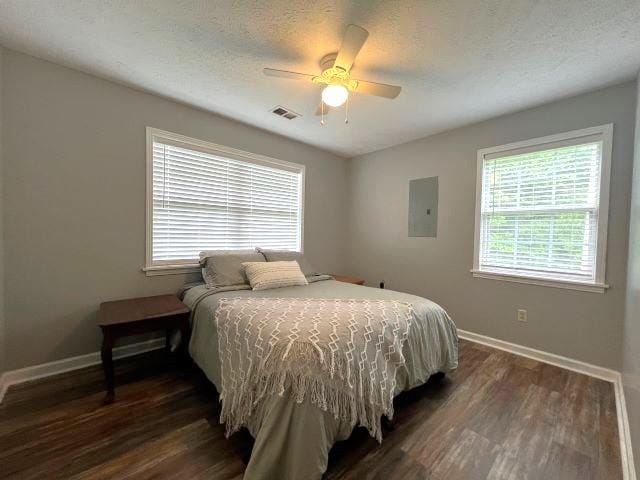 bedroom with a textured ceiling, electric panel, ceiling fan, and dark hardwood / wood-style floors