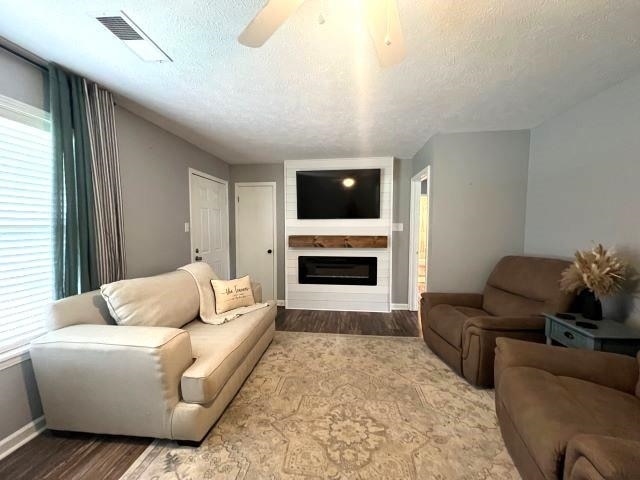 living room featuring ceiling fan, wood-type flooring, and a textured ceiling