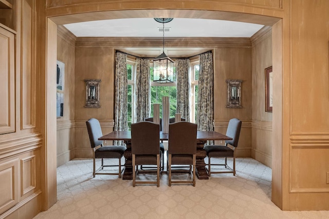 carpeted dining space featuring crown molding and a chandelier