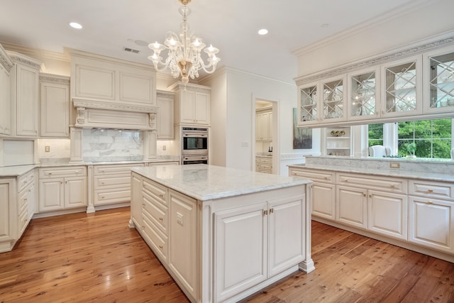 kitchen featuring crown molding, tasteful backsplash, a center island, light wood-type flooring, and pendant lighting