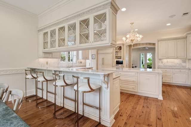 kitchen featuring sink, hanging light fixtures, ornamental molding, paneled fridge, and kitchen peninsula