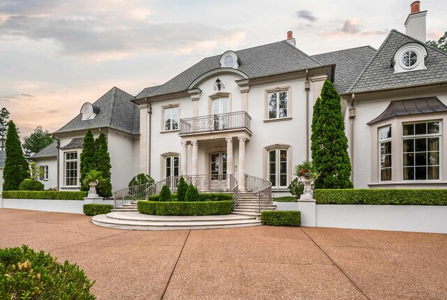 french country inspired facade with a balcony and french doors