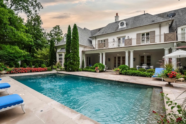 pool at dusk with french doors, ceiling fan, and a patio area