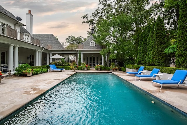 pool at dusk featuring a patio area