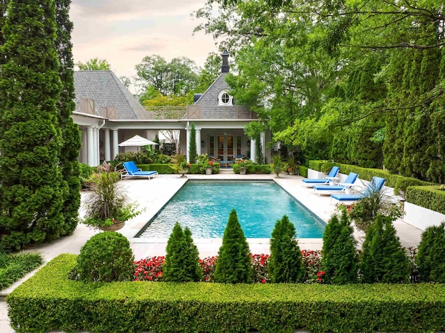 pool at dusk featuring a patio and an outdoor structure