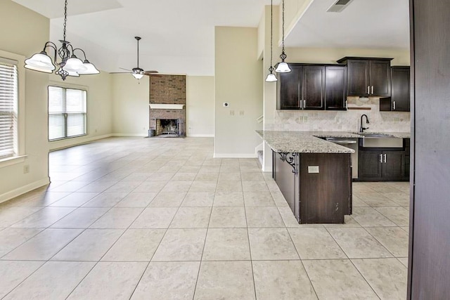 kitchen featuring brick wall, light stone countertops, dark brown cabinetry, a brick fireplace, and backsplash