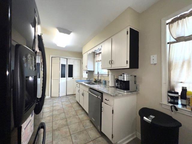 kitchen featuring white cabinetry, dishwasher, light tile patterned flooring, fridge, and sink