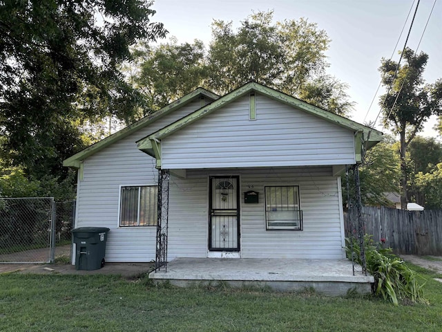 bungalow-style home featuring covered porch and a front yard