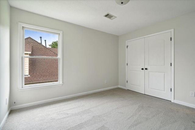 unfurnished bedroom featuring light carpet and a closet