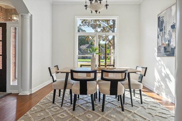 dining area featuring an inviting chandelier, ornamental molding, dark hardwood / wood-style floors, and ornate columns