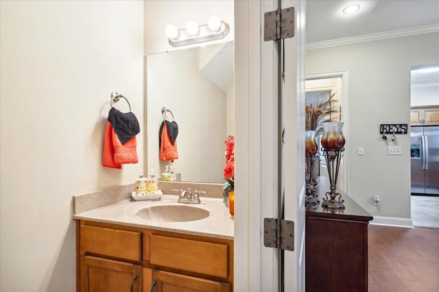 bathroom with crown molding, vanity, baseboards, and wood finished floors