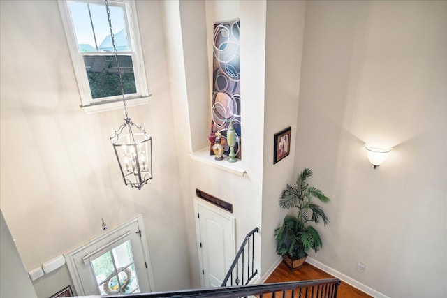 entryway with wood-type flooring, a towering ceiling, and an inviting chandelier