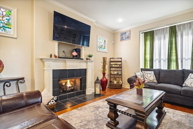 living room featuring ornamental molding, a tile fireplace, baseboards, and wood finished floors