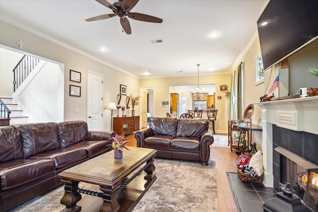 living room featuring crown molding, a fireplace, ceiling fan with notable chandelier, and hardwood / wood-style floors