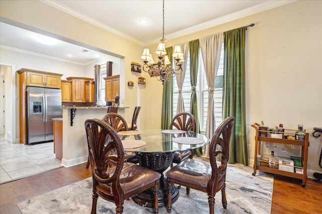 dining area featuring an inviting chandelier, light hardwood / wood-style flooring, and ornamental molding