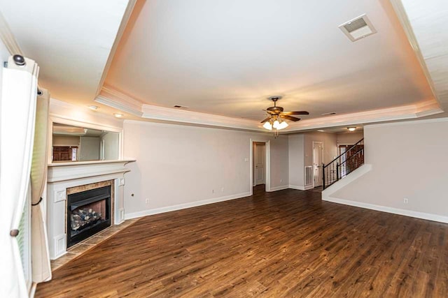 unfurnished living room featuring a fireplace, dark hardwood / wood-style flooring, ornamental molding, ceiling fan, and a raised ceiling