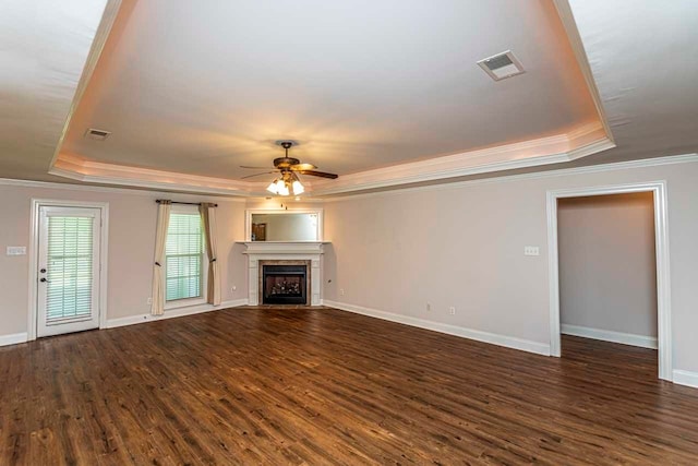 unfurnished living room with dark hardwood / wood-style floors, a fireplace, a tray ceiling, and ceiling fan