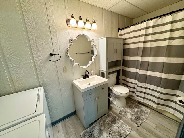 bathroom with vanity, wood-type flooring, wood walls, toilet, and washer / clothes dryer