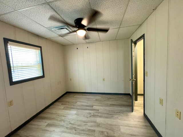 empty room featuring light hardwood / wood-style floors, a drop ceiling, and ceiling fan