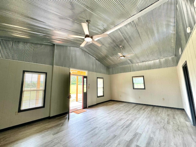 empty room featuring wood-type flooring, vaulted ceiling, a wealth of natural light, and ceiling fan