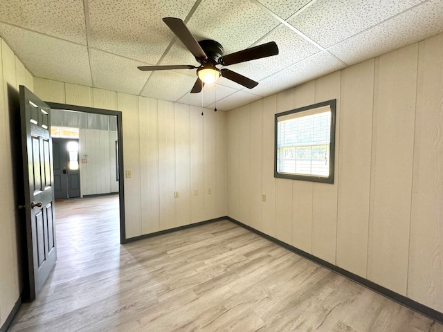 spare room with a paneled ceiling, light wood-type flooring, and ceiling fan