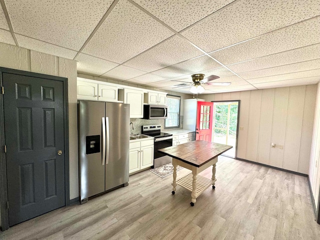 kitchen with a paneled ceiling, light wood-type flooring, stainless steel appliances, and white cabinets