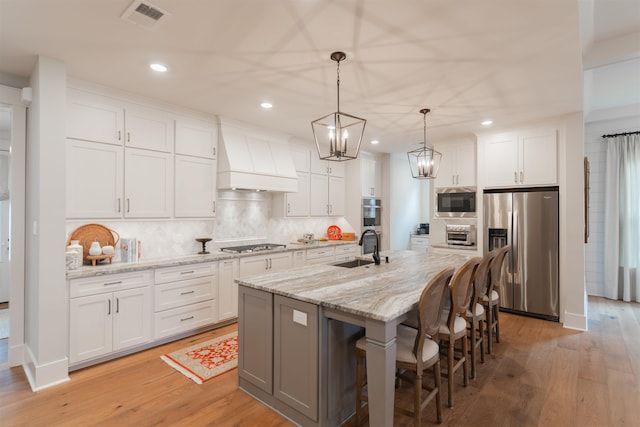 kitchen featuring appliances with stainless steel finishes, light hardwood / wood-style flooring, white cabinets, and sink