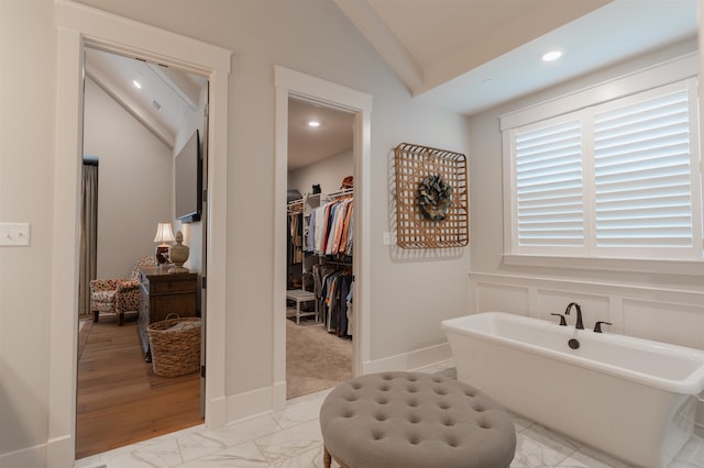 bathroom featuring a tub, lofted ceiling, and hardwood / wood-style flooring