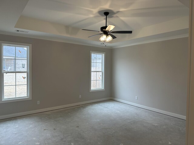 empty room featuring ceiling fan, a healthy amount of sunlight, a tray ceiling, and ornamental molding