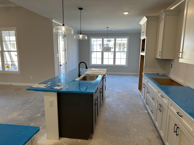 kitchen featuring white cabinetry, sink, and an island with sink