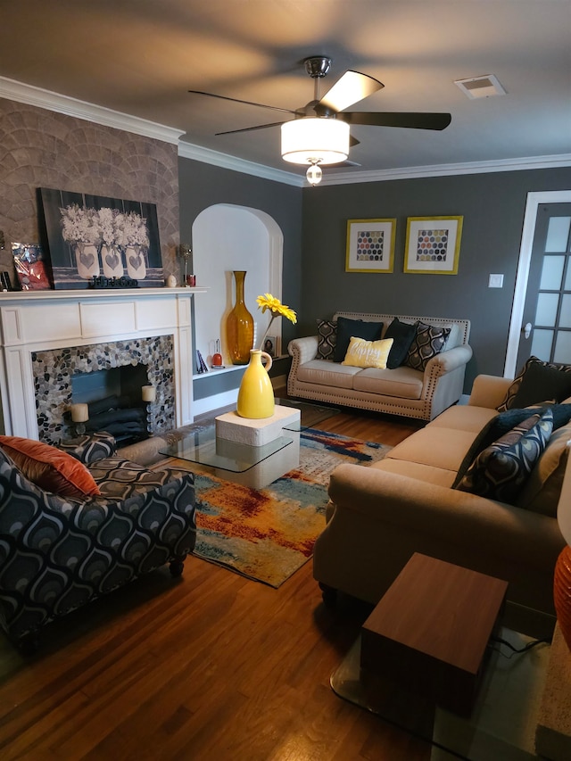 living room featuring crown molding, hardwood / wood-style flooring, a fireplace, and ceiling fan