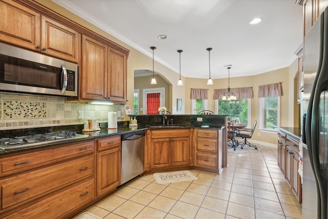 kitchen with appliances with stainless steel finishes, sink, backsplash, hanging light fixtures, and kitchen peninsula