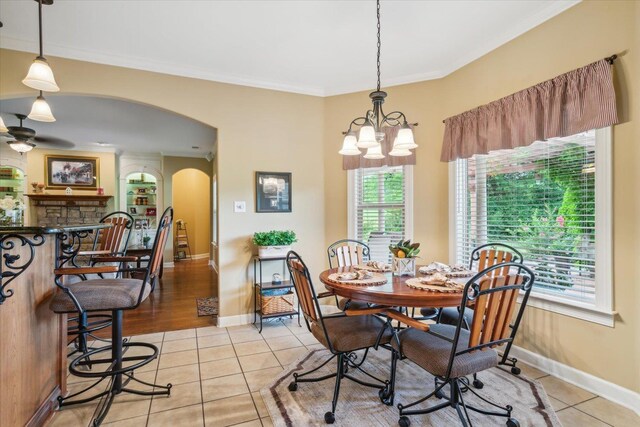 tiled dining area with crown molding, ceiling fan, and a fireplace