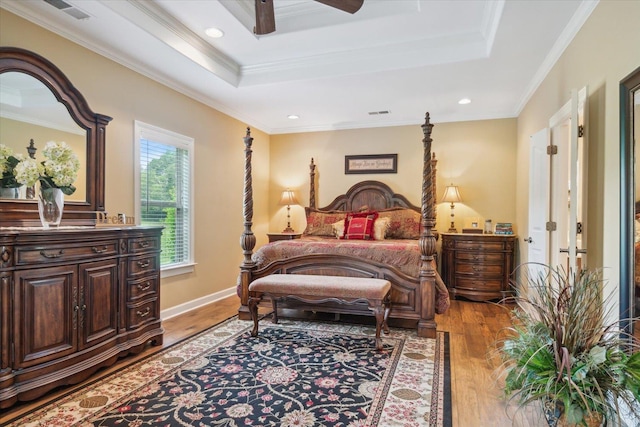 bedroom featuring crown molding, hardwood / wood-style flooring, and a raised ceiling