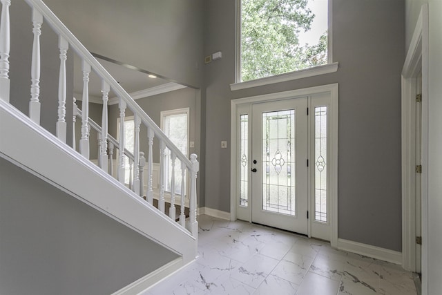 foyer with a towering ceiling and ornamental molding