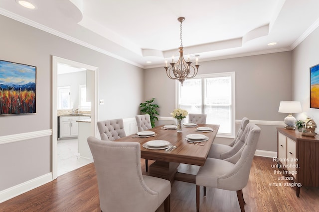 dining space with a raised ceiling, crown molding, an inviting chandelier, and dark hardwood / wood-style flooring