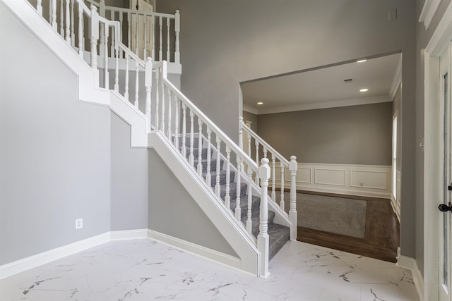 stairs with crown molding and a high ceiling