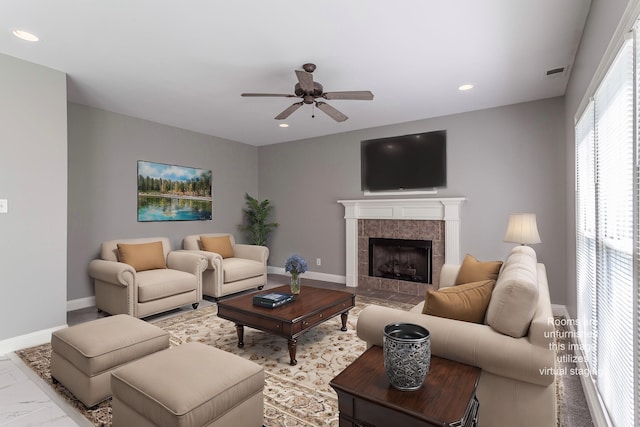 living room featuring a tile fireplace and ceiling fan