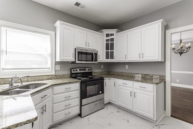 kitchen with sink, appliances with stainless steel finishes, white cabinetry, an inviting chandelier, and dark stone counters