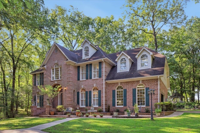 colonial home featuring a front yard and brick siding