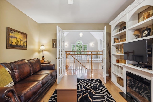 living area with a fireplace with flush hearth and light wood-style flooring