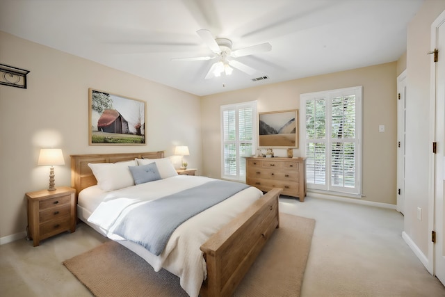 bedroom with ceiling fan, light colored carpet, visible vents, and baseboards