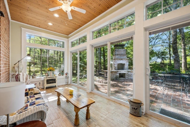 sunroom / solarium with ceiling fan, a wealth of natural light, and wood ceiling