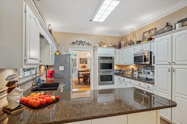 kitchen featuring appliances with stainless steel finishes, white cabinets, a sink, and dark stone counters