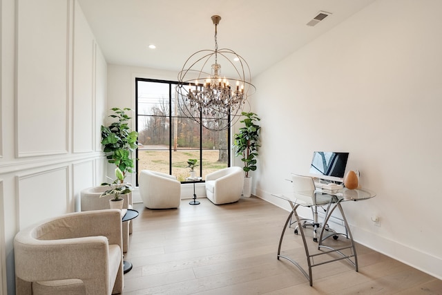 living area featuring light hardwood / wood-style flooring, an inviting chandelier, and lofted ceiling