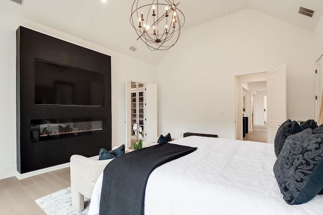 bedroom with light hardwood / wood-style flooring, high vaulted ceiling, and a chandelier