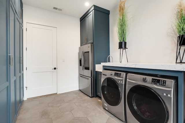 laundry area with separate washer and dryer and light tile patterned floors