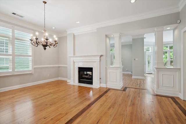 unfurnished living room with decorative columns, ornamental molding, and light hardwood / wood-style flooring